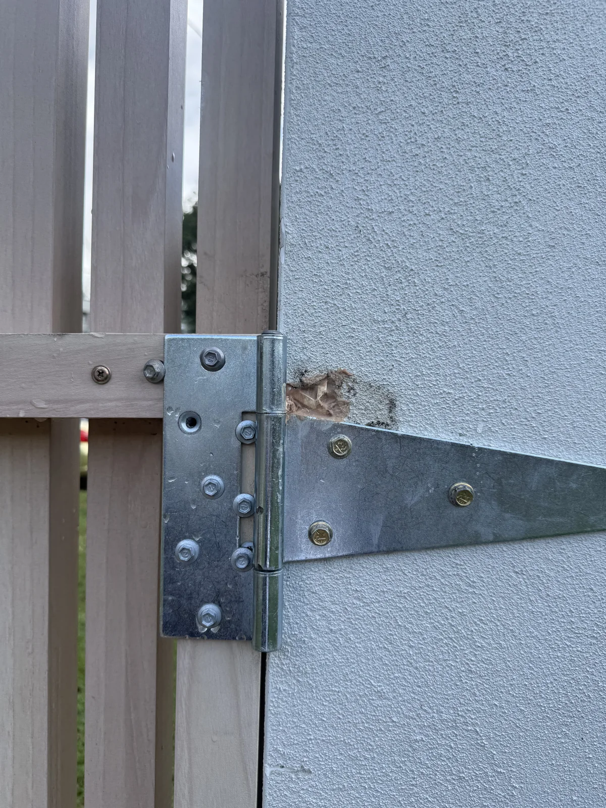 Chipped rendered gate pillar around the existing hinge before repair